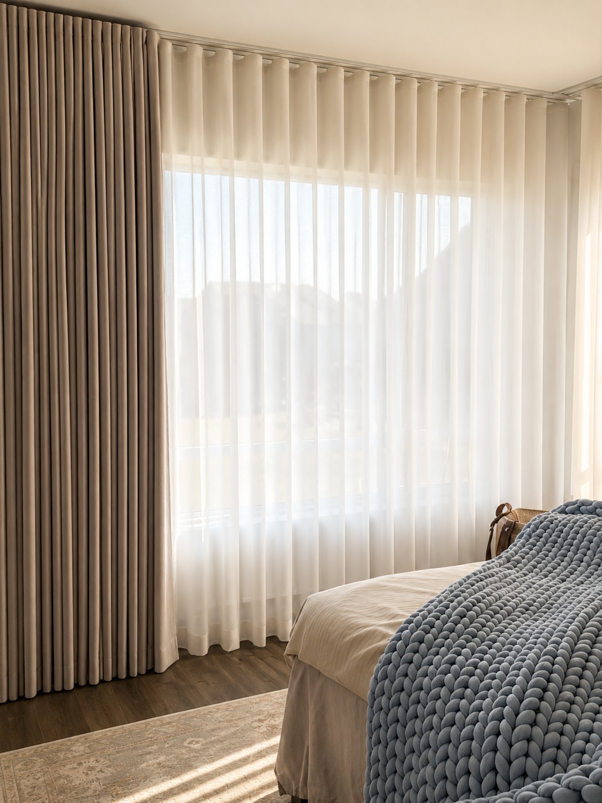 Sheer wave curtains layered with a blackout drape on a ceiling track