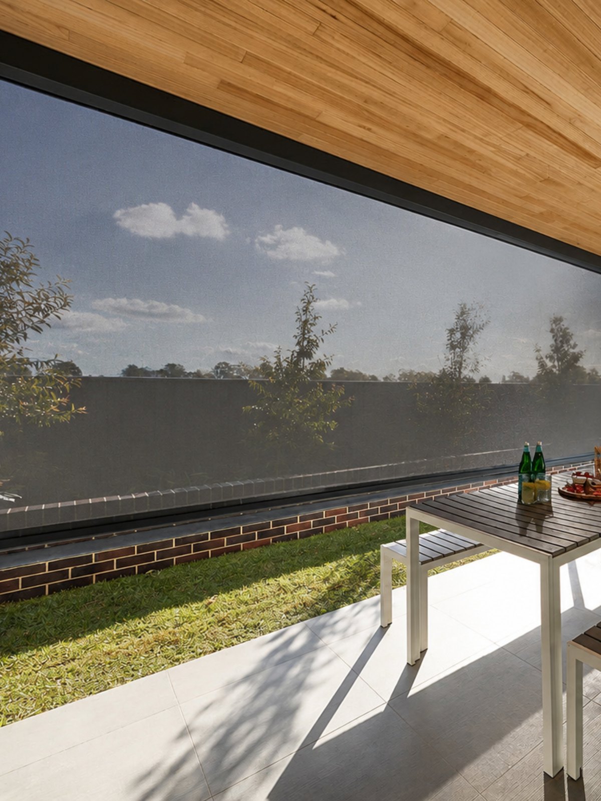 A heavy-duty zip-track outdoor blind enclosing a covered patio